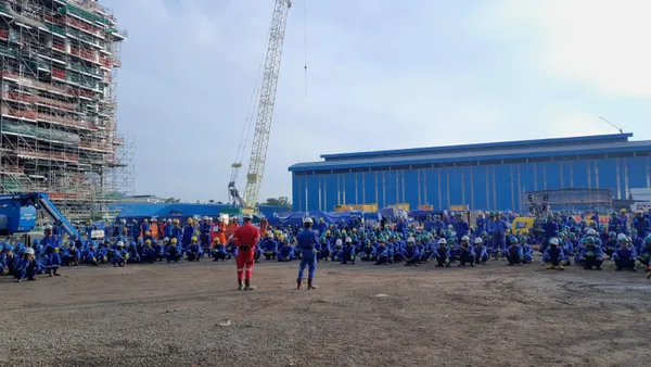 A group of people sit and stand on a jobsite.