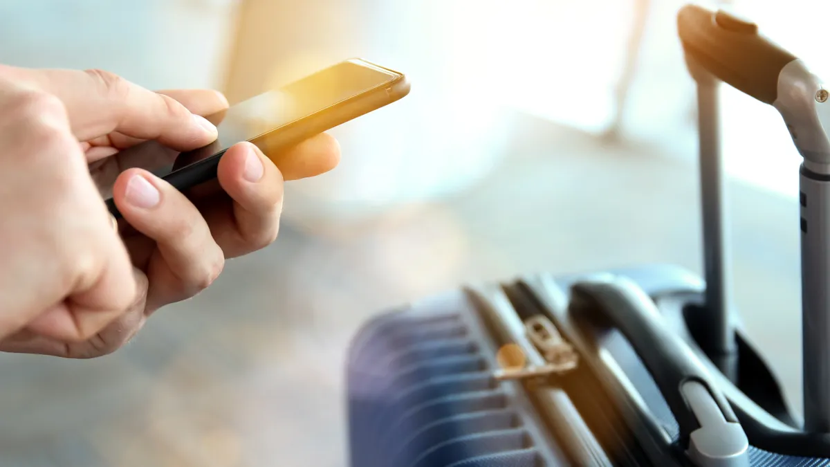 Person holding phone near suitcase