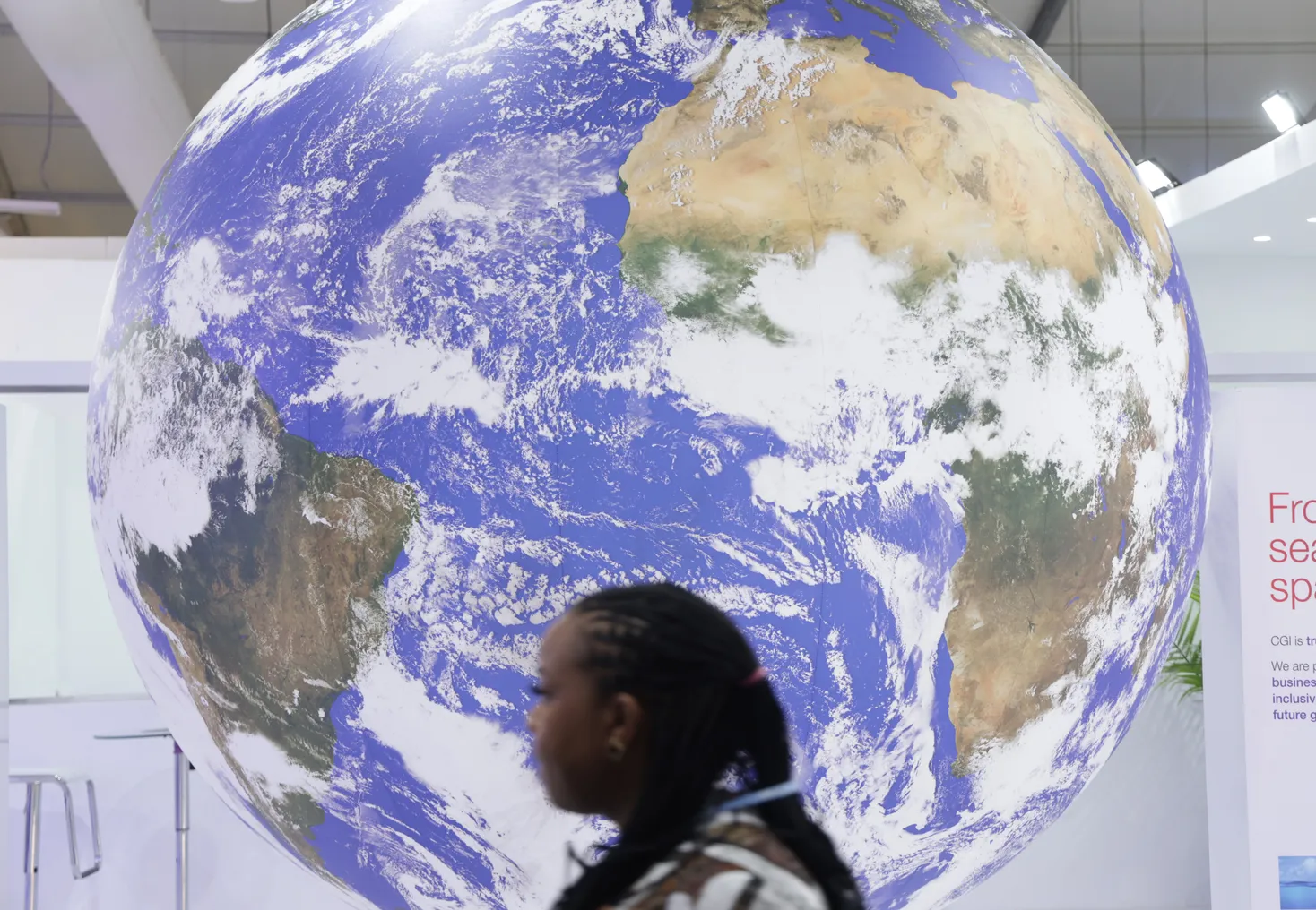 A conference participant walks past a spinning representation of Planet Earth during the UNFCCC COP27.