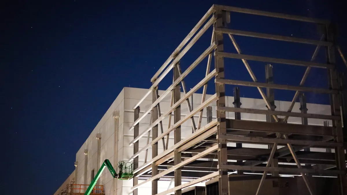 A white data center under construction is seen under a night sky with stars.