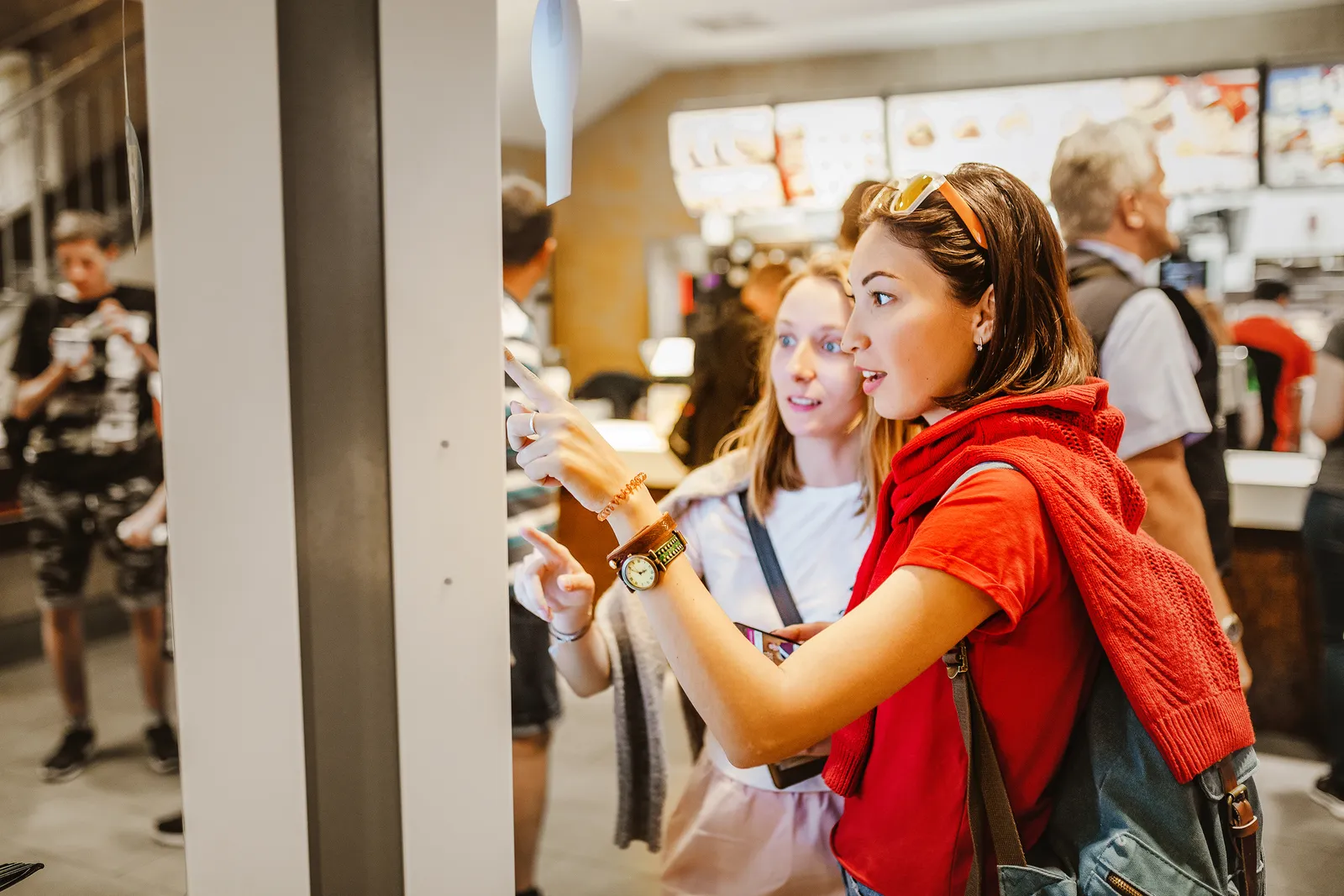 A woman orders food in the touch screen terminal with electronic menu in fast food restaurant