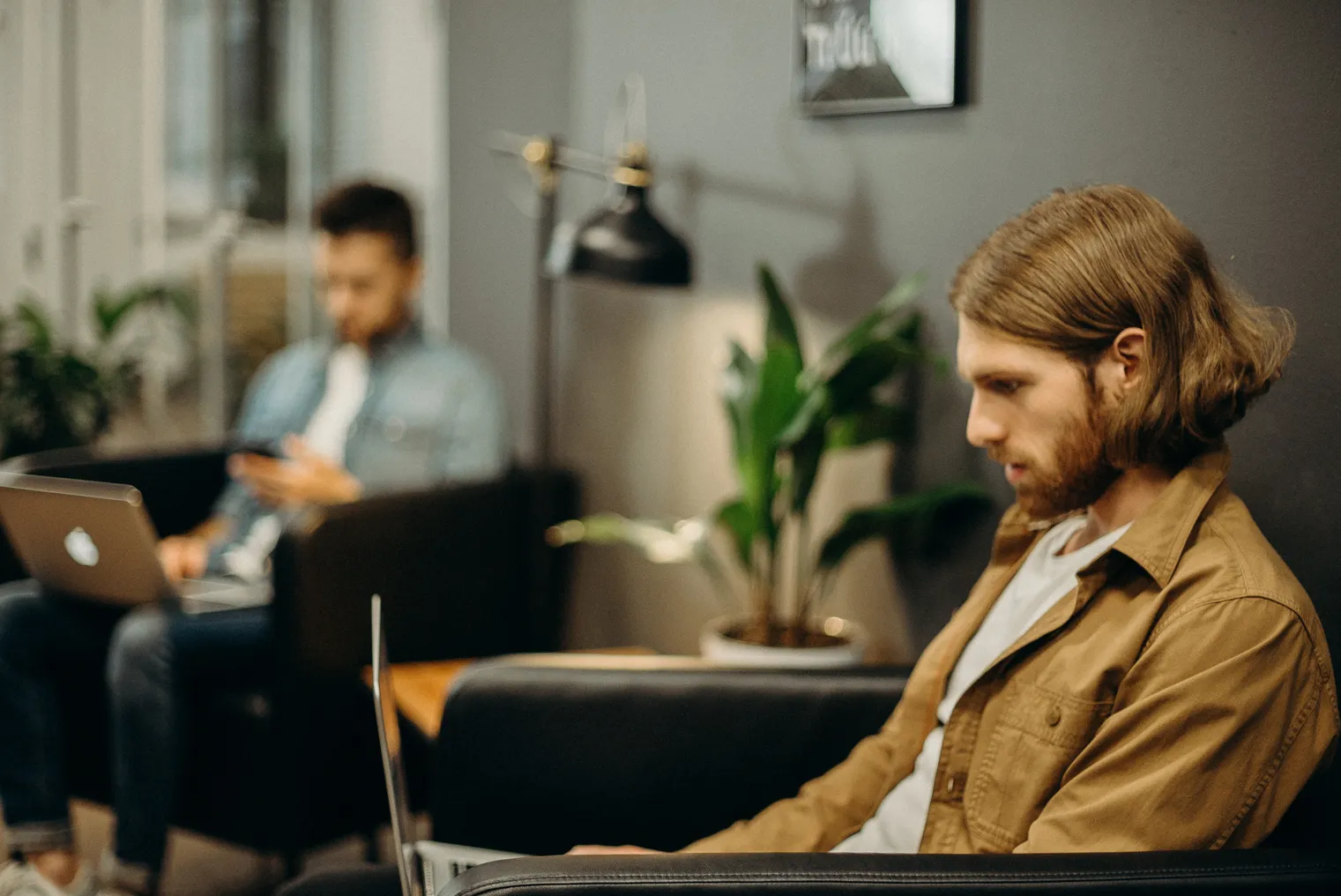 Side profile: a White man with long hair and a beard works on a laptop