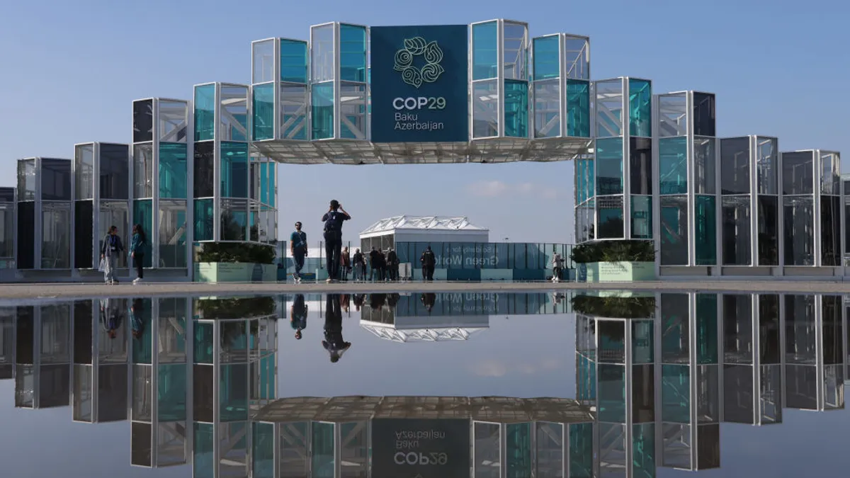 People are reflected in a puddle outside the COP29 conference venue