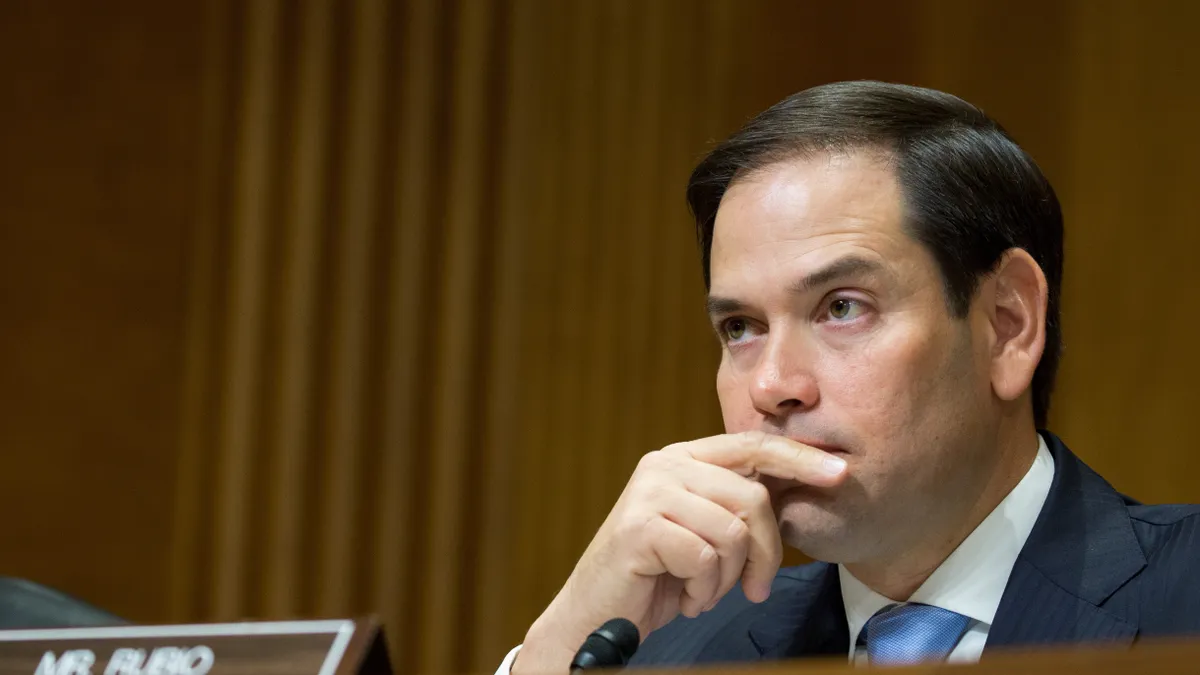 A close-up of a man with short black hair listening intently to something out of frame.