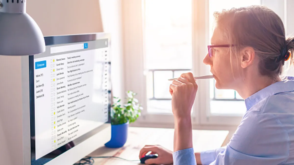 Business person reading emails on computer screen while working from home