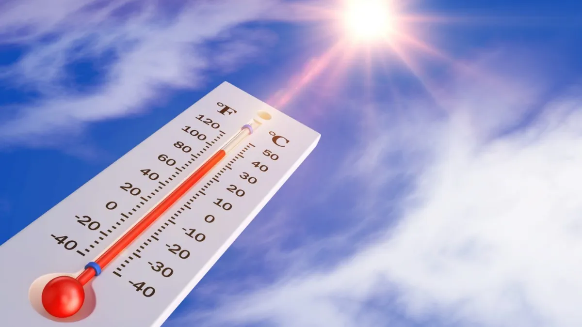 A white thermometer set to 100 degrees pointing at the sun surrounded by the blue sky