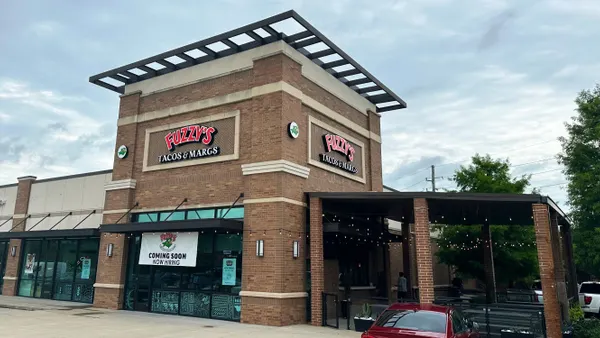 A photograph of a brick building with signage that says "Fuzzy's Tacos and Margs."