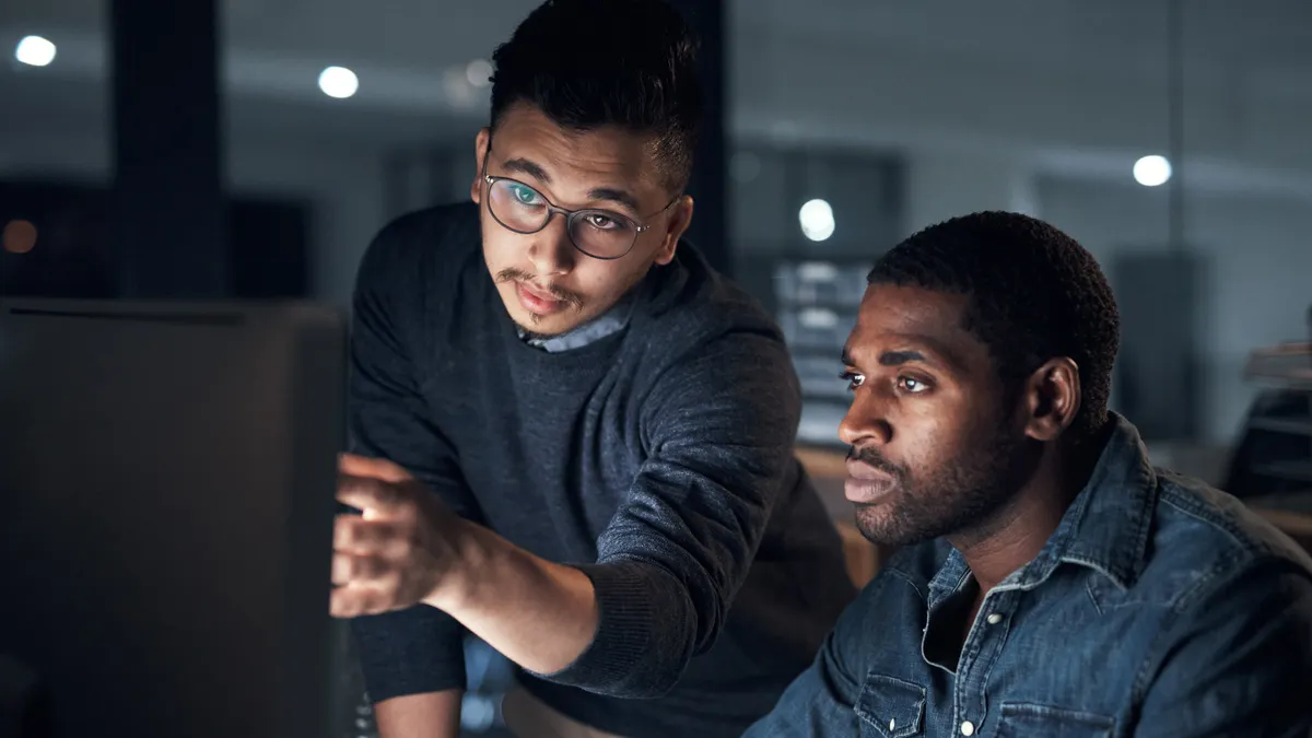Shot of two young businessmen using a computer during a late night in a modern office