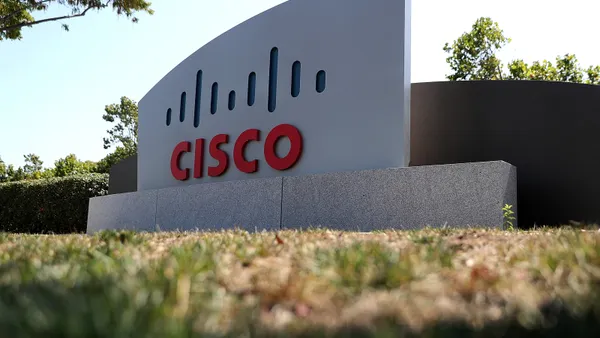 A large sign says "Cisco" in red letters. The sign sits on a grassy lawn.
