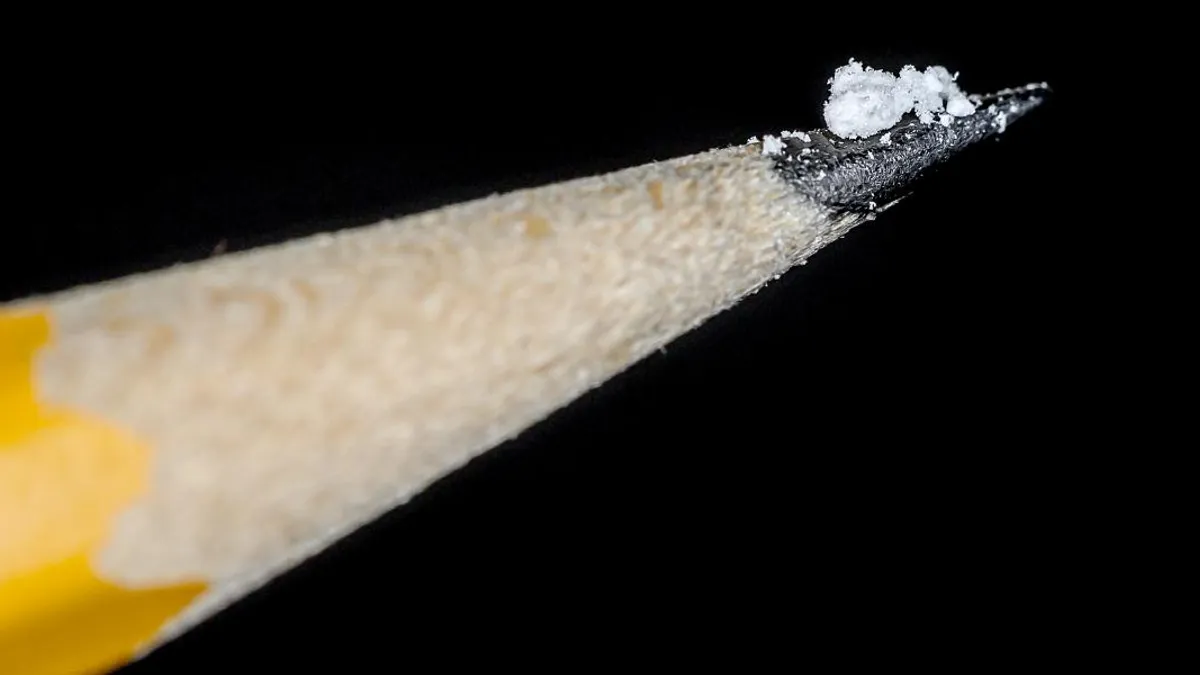 A lethal dose of fentanyl is shown on the tip of a pencil against a black background.