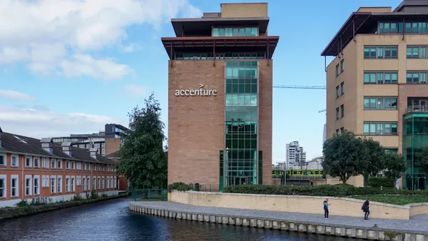 A building emblazoned with the Accenture corporate logo located near a canal in Dublin.