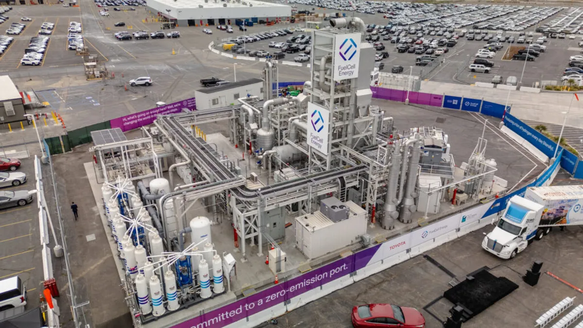 Birds eye view of hydrogen tanks surrounded by a wire fence and cars.