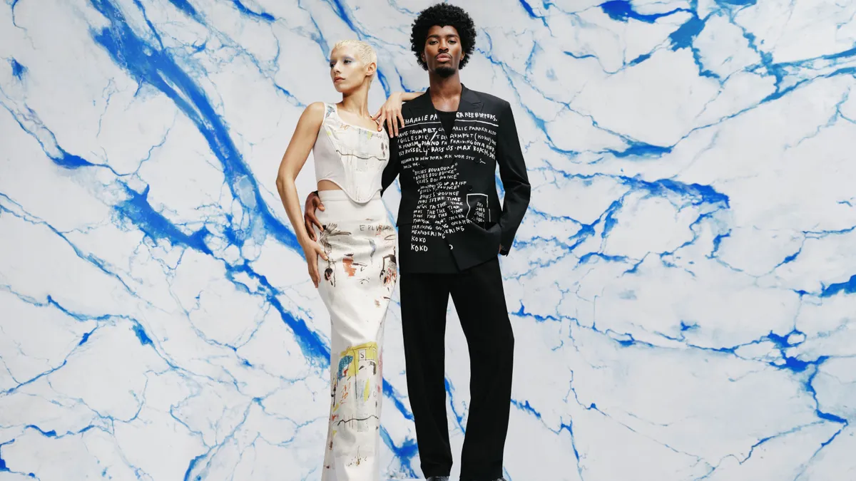 Two models wear distressed denim outfits featuring artwork by Jean-Michel Basquiat.