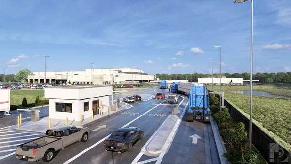 Cars enter a warehouse parking lot with a warehouse in the background.