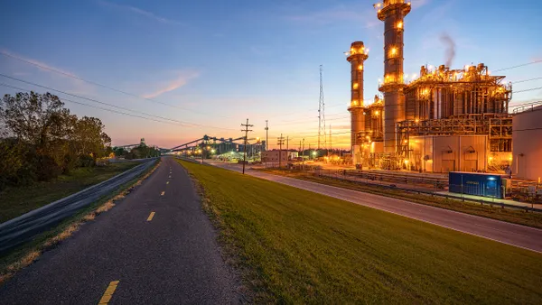 A brightly lit power plant next to a road.