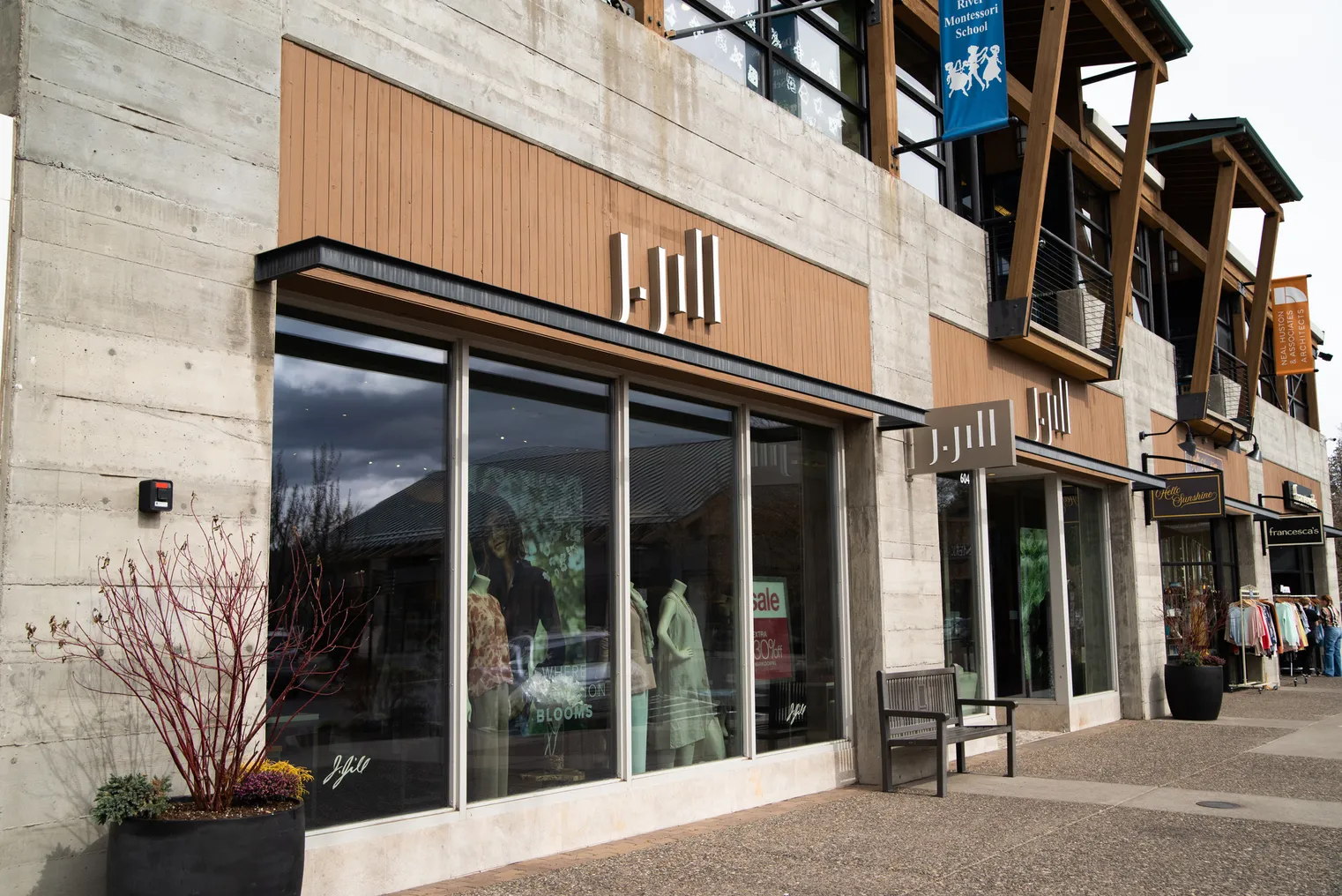 Block letters on wood paneling and a small sign jutting from a light stone building all read "J. Jill," above a store window.