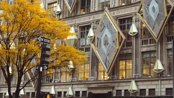 A tree with yellow leaves in front of a department store with massive holiday decorations.