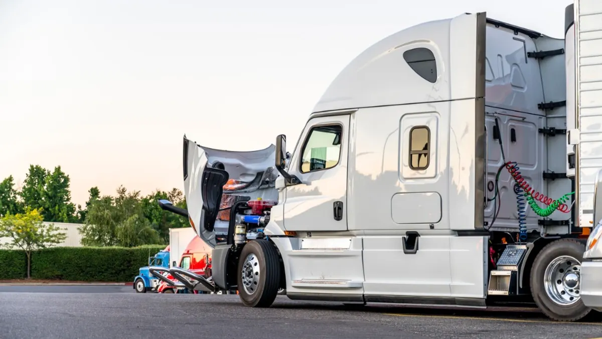 A white semi truck with the hood open.