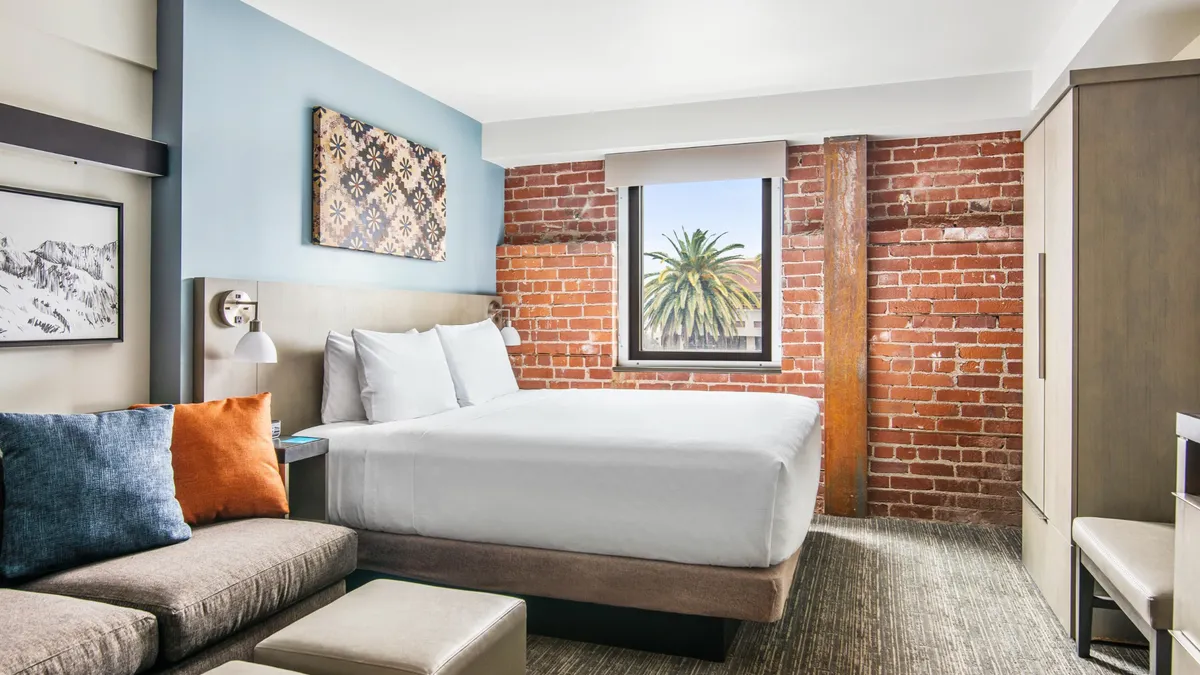 A guestroom with a white bed and brick walls.