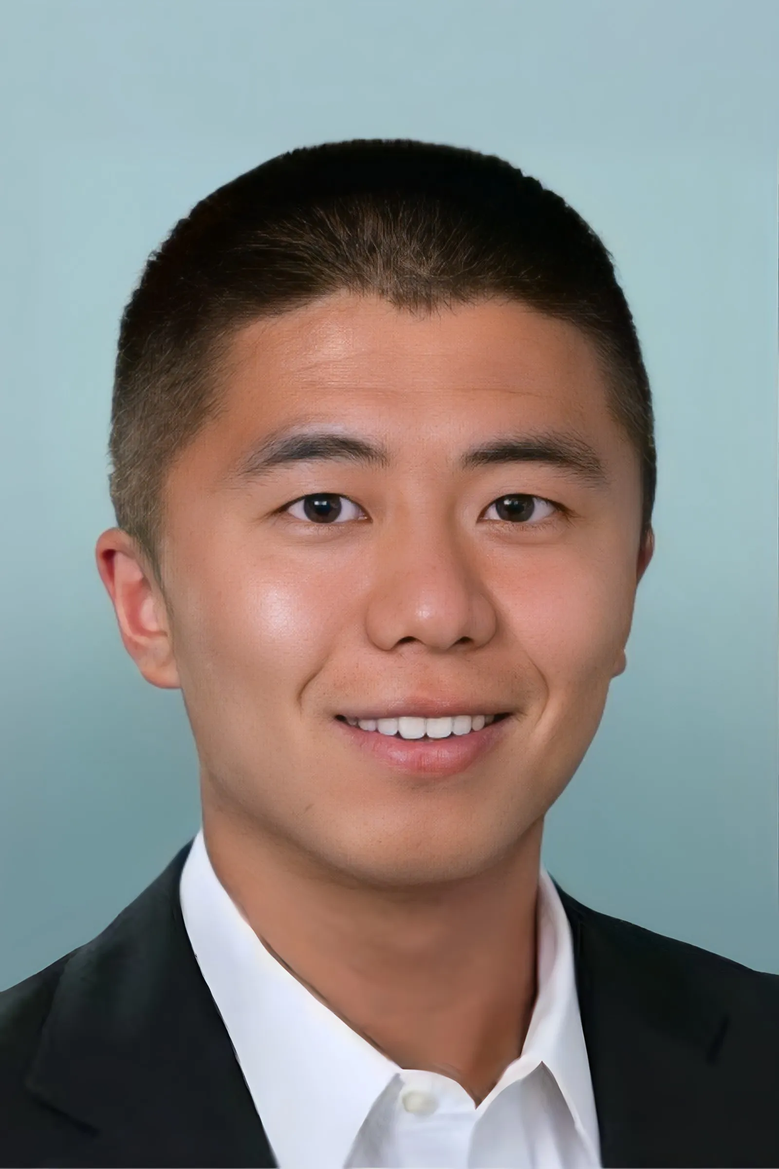 Dark haired man in dark jacket and white shirt.