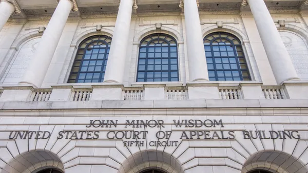 The front facade of a courthouse is shown, bearing the words "John Minor Wisdom United States Court of Appeals Building Fifth Circuit"