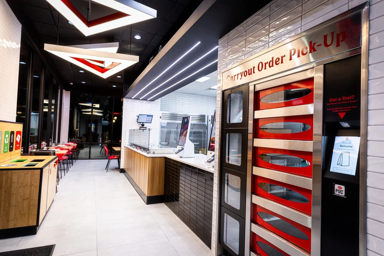 A store interior with white tile, red accents and pickup cabinets.