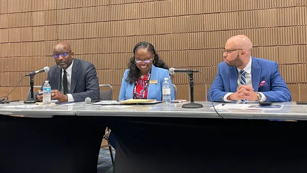 Three school superintendents of color are seated at a table during a conference session.