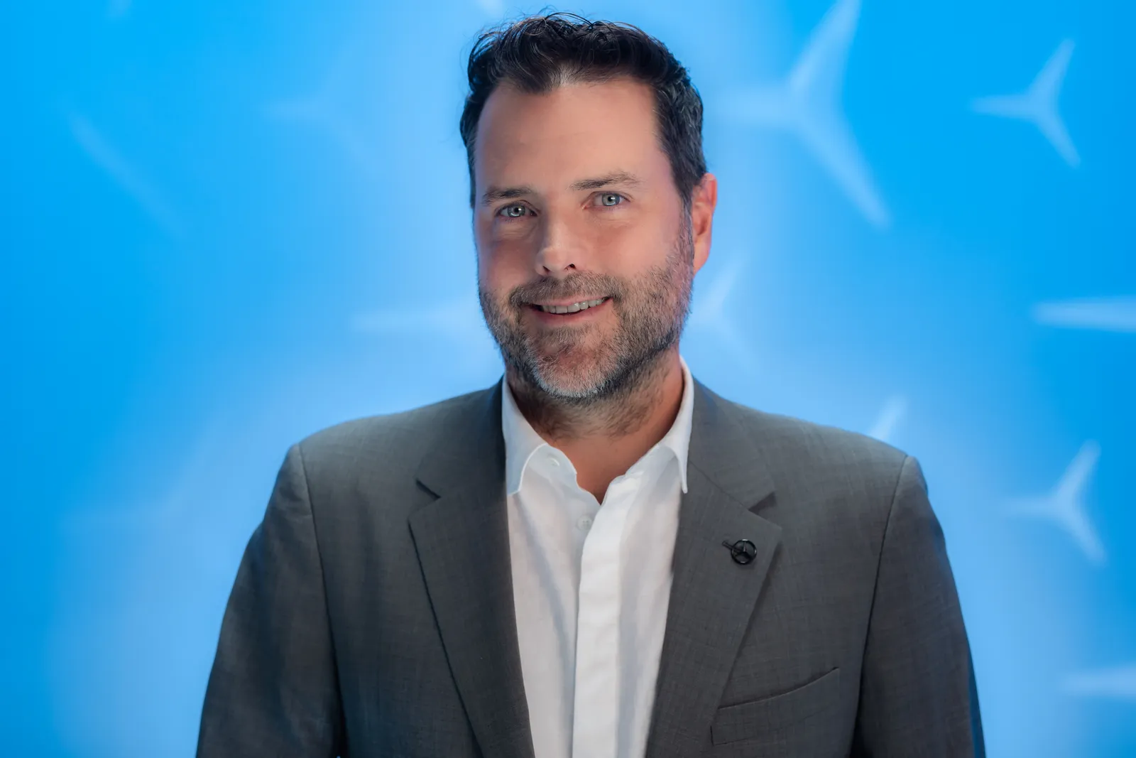 A man in a suit with a blue background