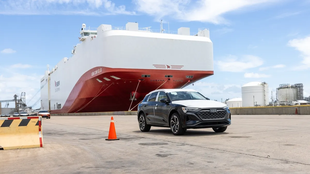 An Audi vehicle stands in front of a Ro/Ro vessel.