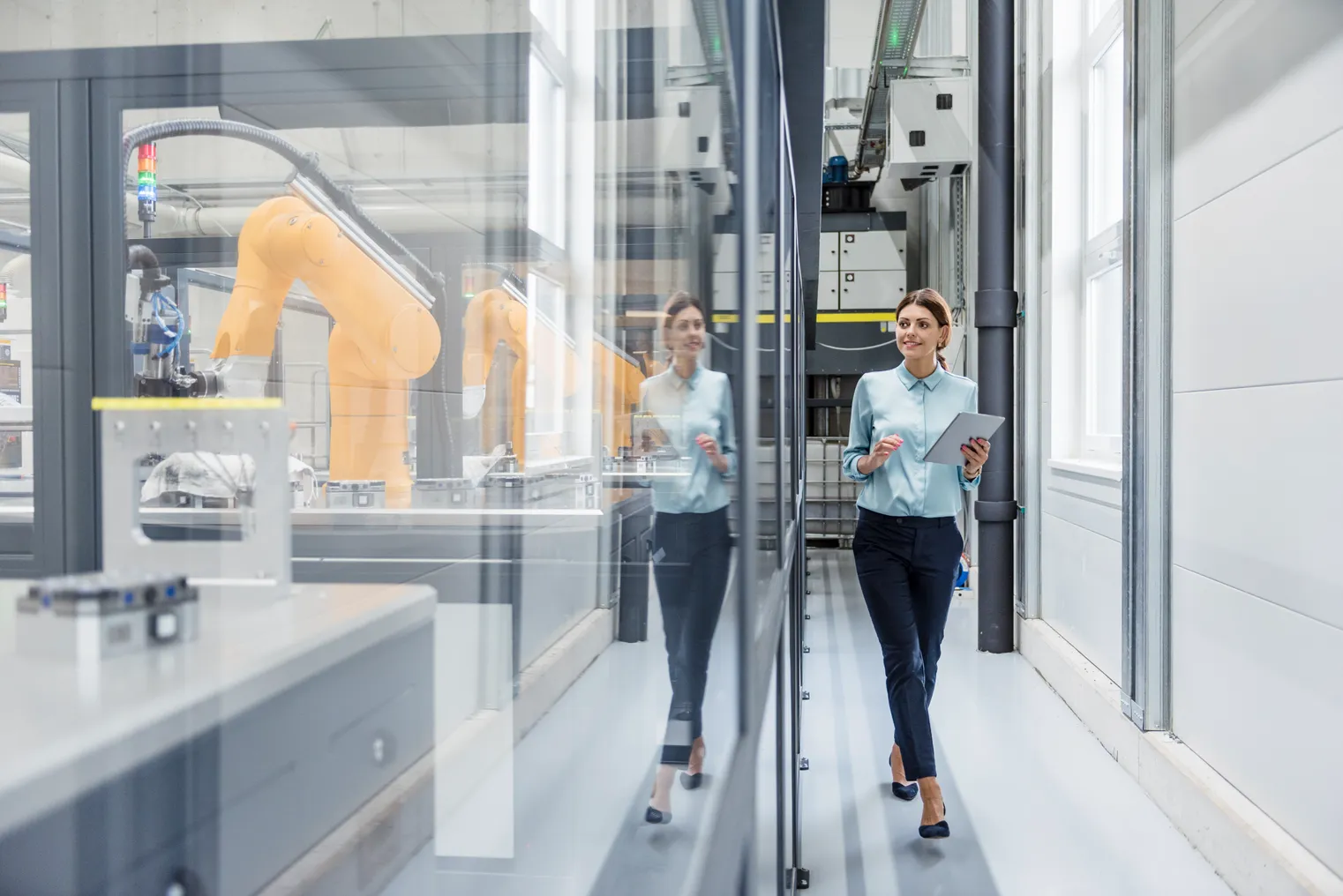 Businesswoman checking robots with digital tablet in high tech company