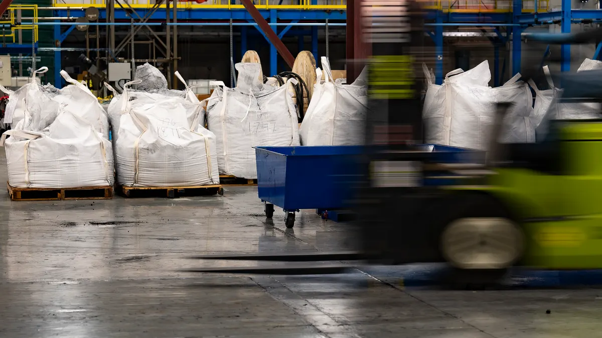 a forklift drives by sacks of batteries in a warehouse