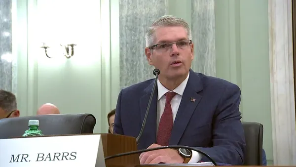 Derek Barrs speaks into a microphone for testimony before a Senate committee in July 2025 regarding his nomination.