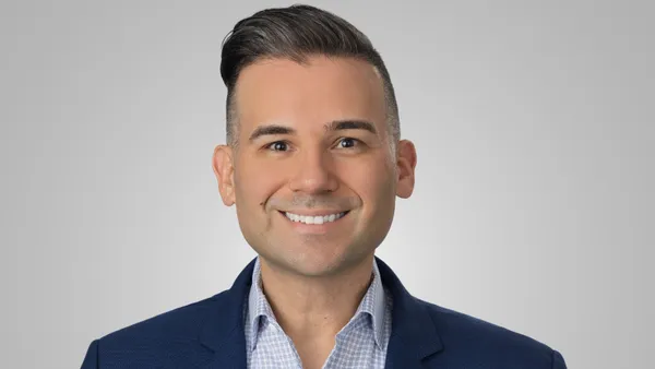 A smiling person in a blue suit jacket.