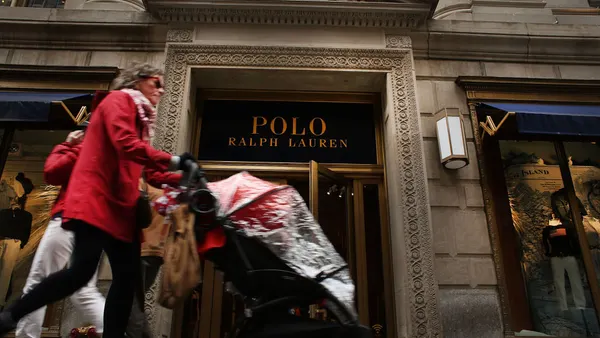 A person pushing a stroller walks by a storefront.