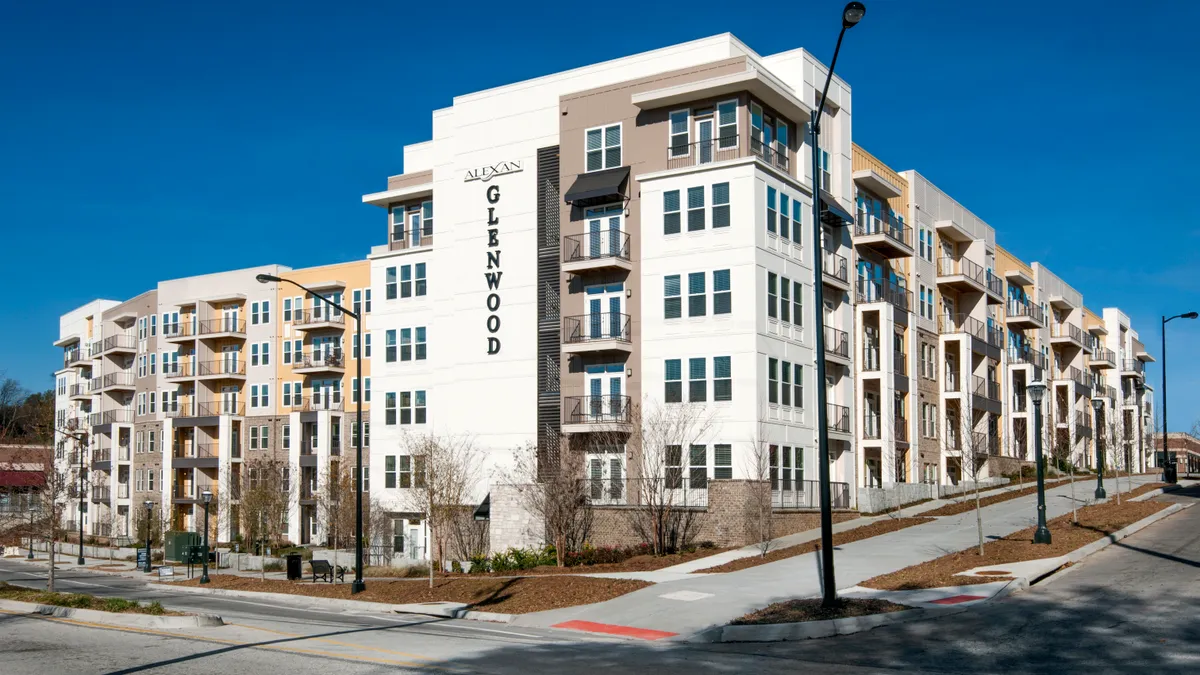 White and brown five-story apartment buildings with street in front and to the right.