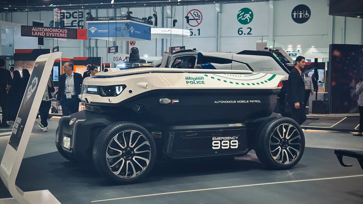 A vehicle that says "POLICE," "Autonomous Mobile Patrol" and "Emergency 999" on a showroom floor at a trade show