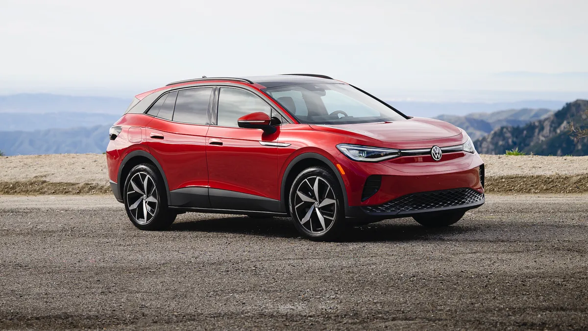 A red 2024 Volkswagen ID.4 SUV on a gravel surface with hills in the background.