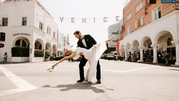 A bridge and Groom in front of of a Venice banner in Venice Beach.