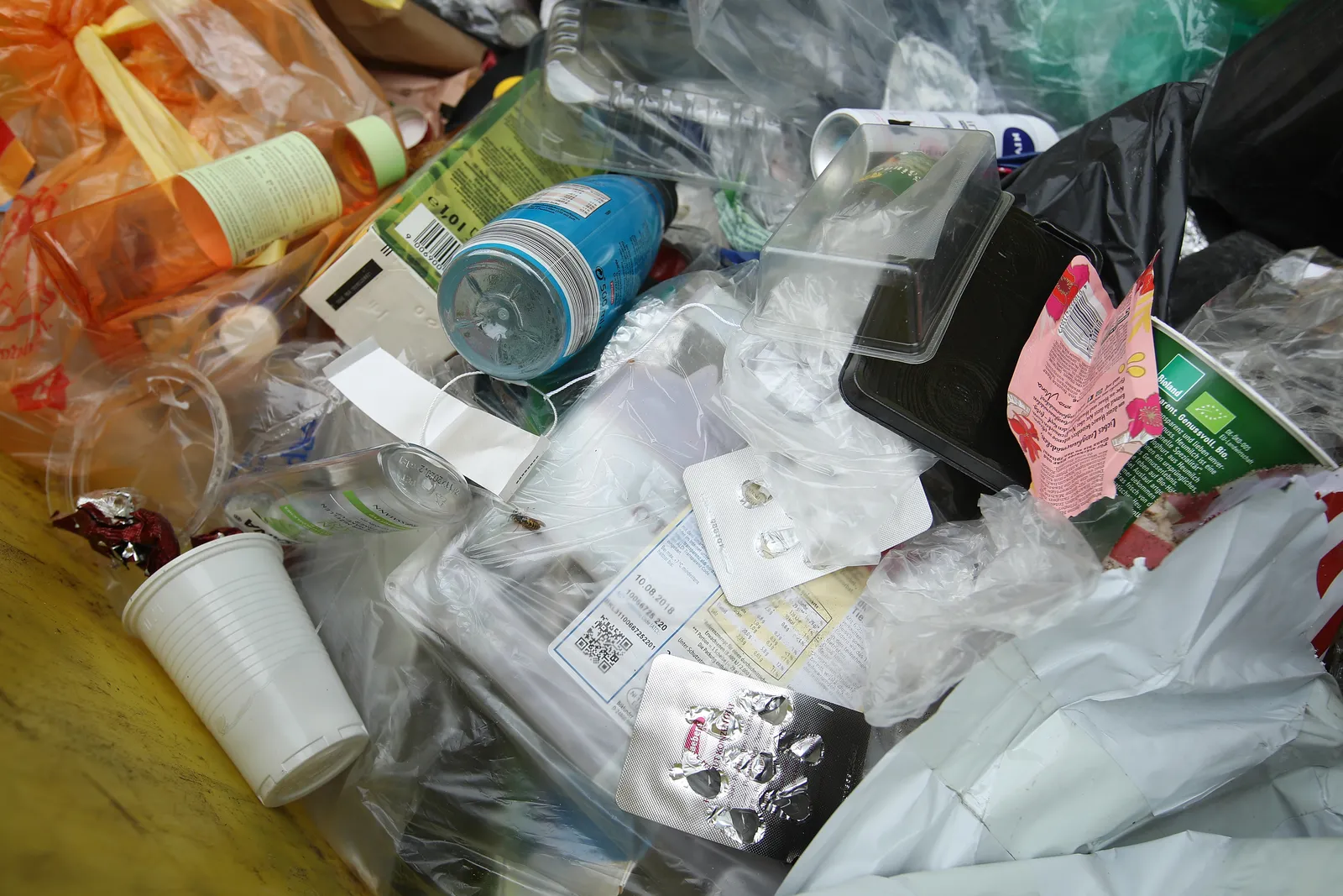 Used food packaging and containers are commingled in a trash receptacle.