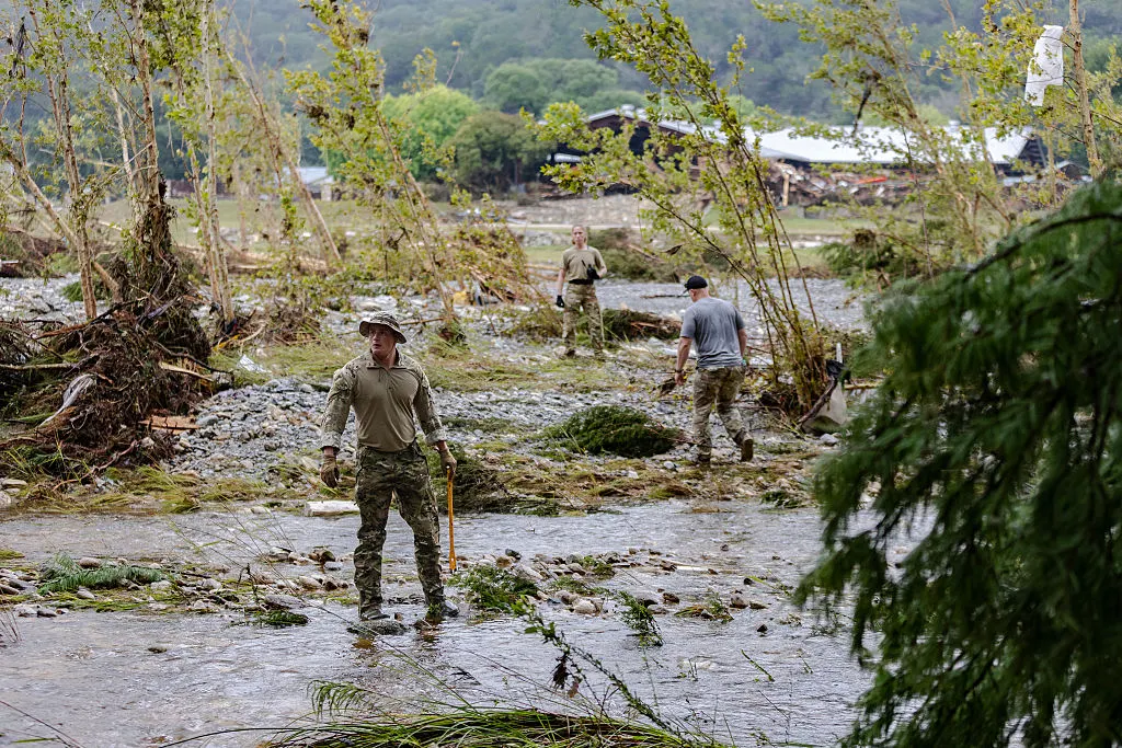 Search and rescue workers walk over flooded areas and natural debris, looking for survivors.