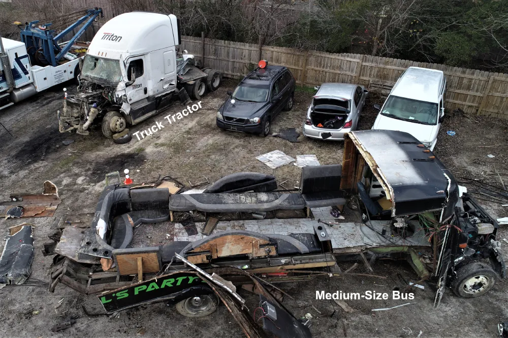 The tractor and party bus shown in a tow yard following the crash, showing the destruction that came from the crash.