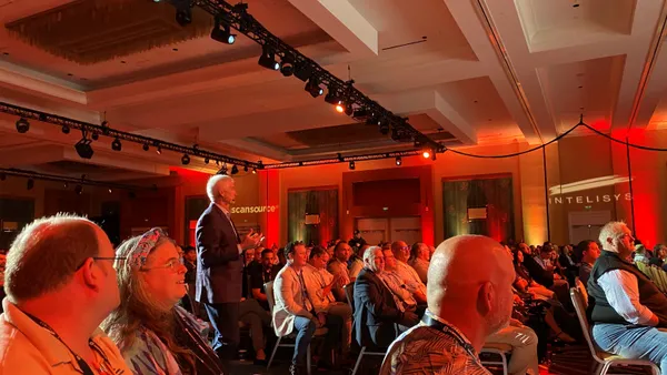 man in a suit walks in a space between rows of audience members