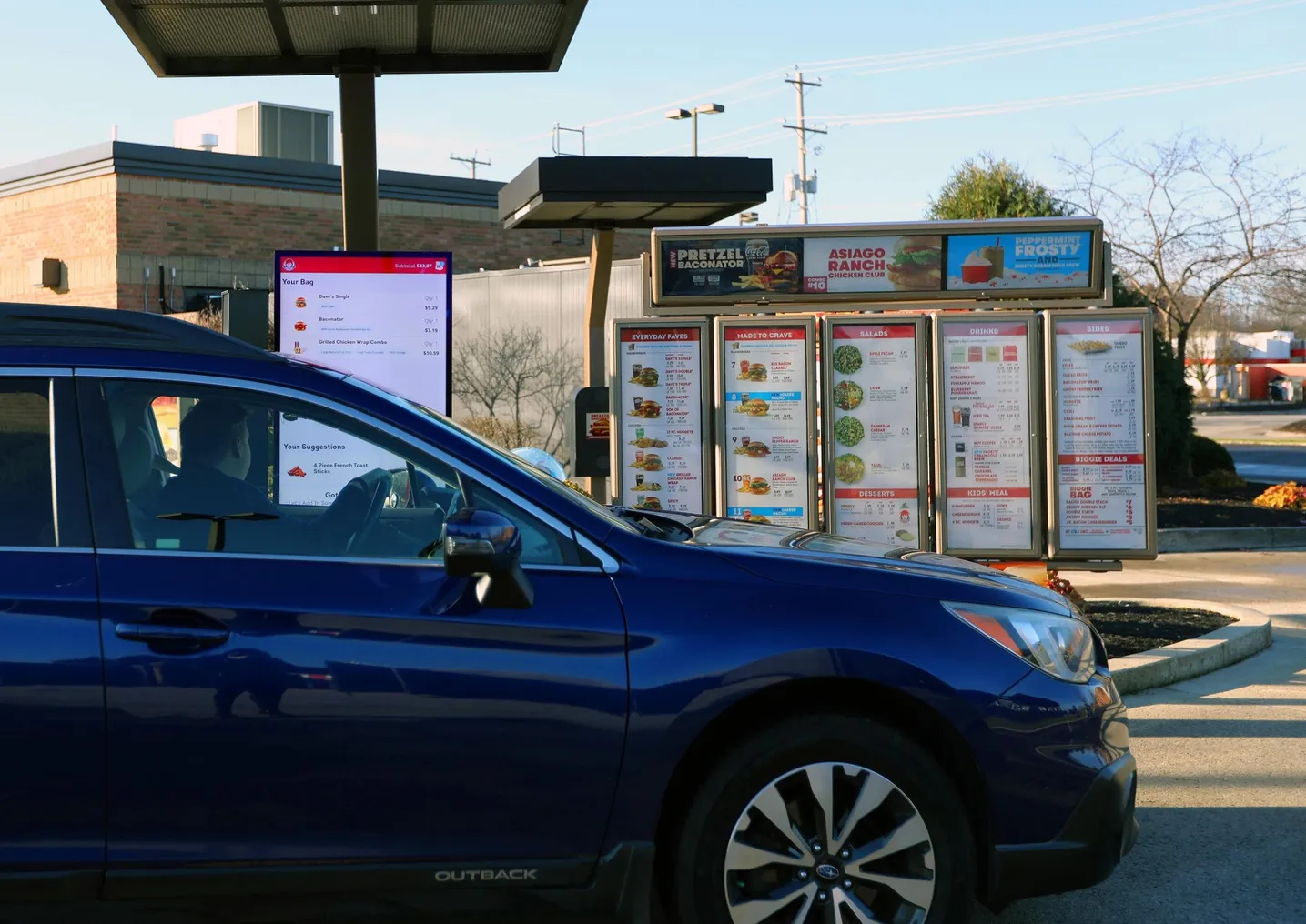 A man in a dark car at a Wendy's drive-thru that uses artificial intelligence to take orders