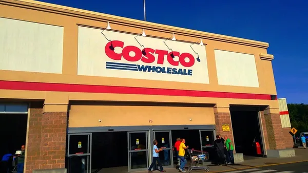 The sun shines brightly on a storefront, against a blue sky.