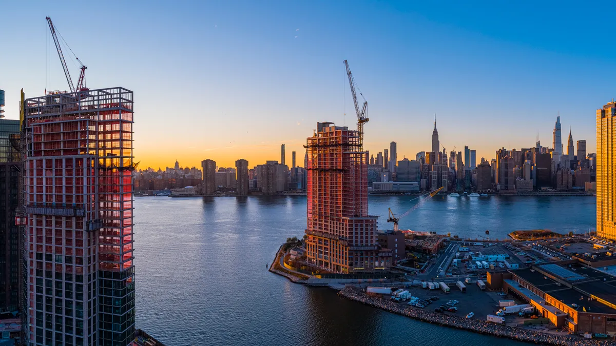 A panoramic shot in New York City shows construction cranes dotting the skyline.