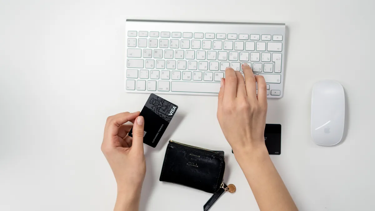 hand typing on keyboard while holding debit card