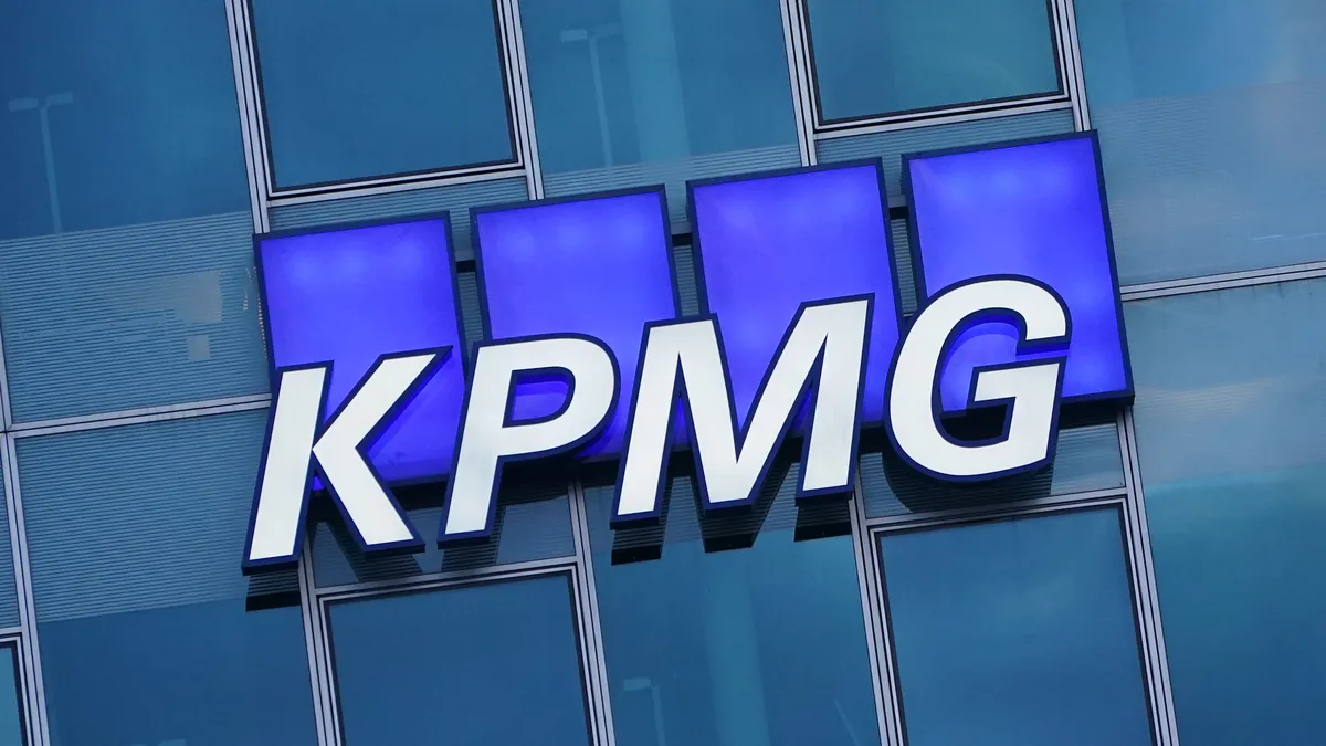 The logo of KPMG hangs on the facade of a building.