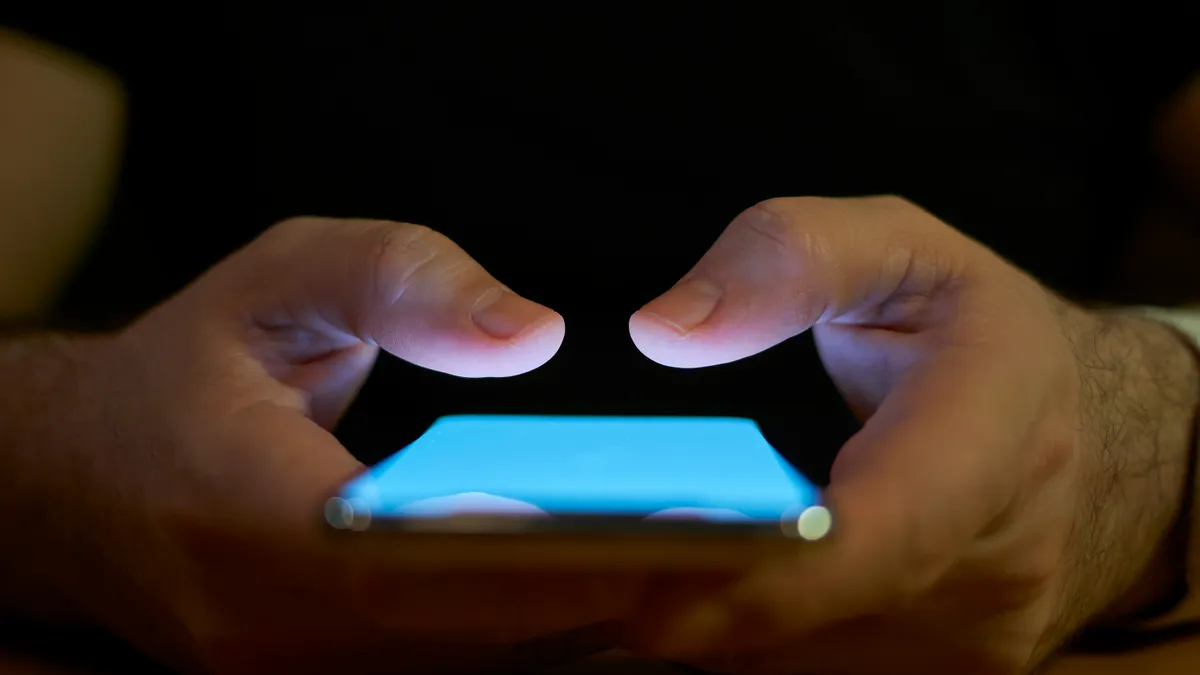 A close up shot of a person's hands typing on a touchscreen phone.