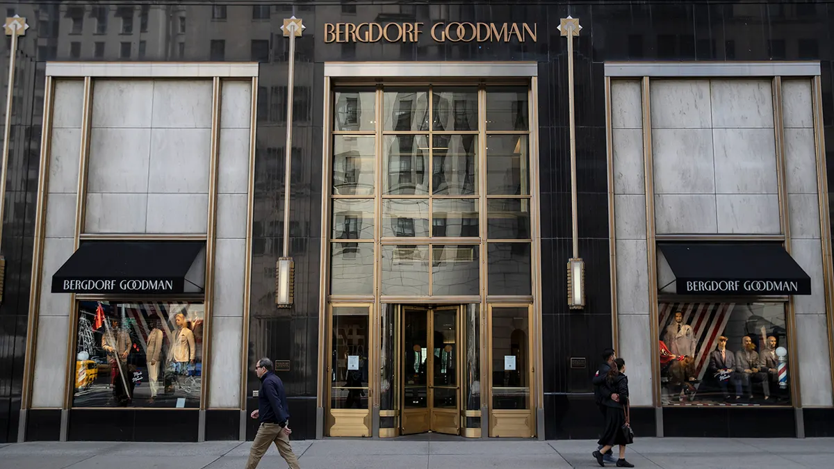 The side of a building made of light brick exterior and a placard reading BERGDORF GOODMAN