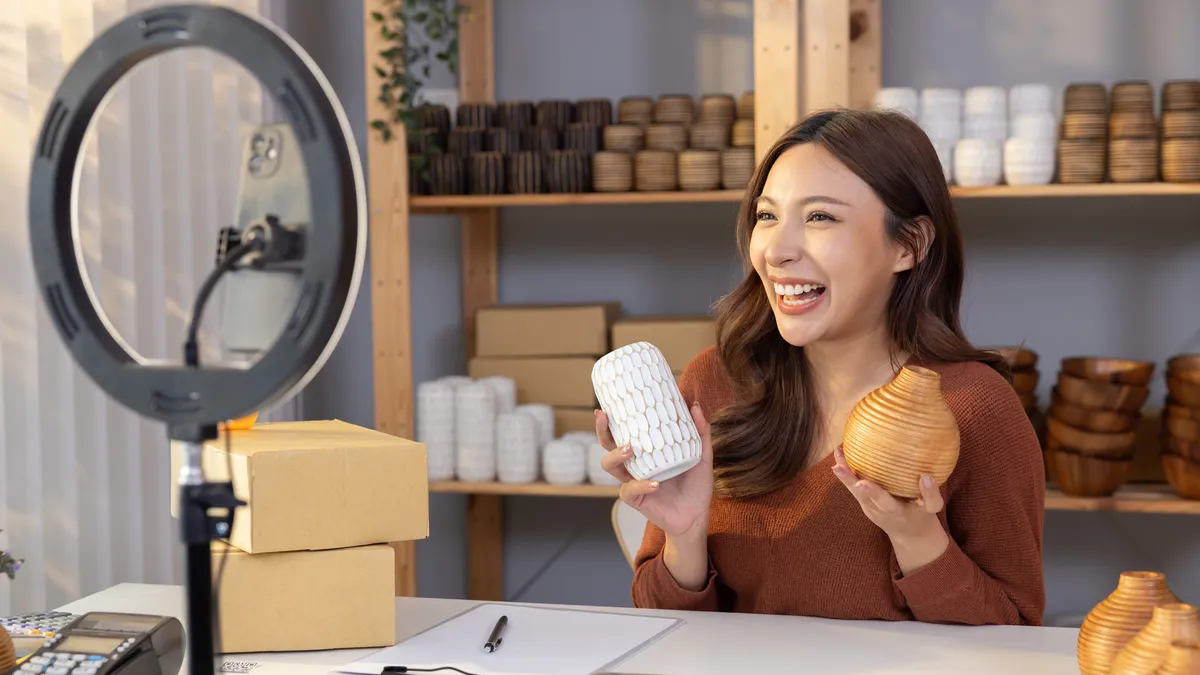 Person sitting in front of ring light, holding up products